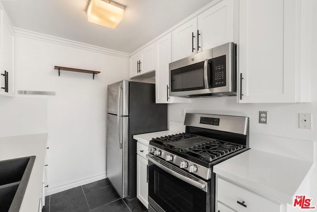 kitchen with white cabinetry, stainless steel appliances, dark tile patterned flooring, crown molding, and sink