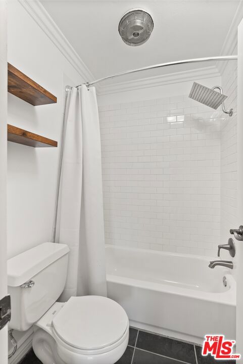 bathroom featuring toilet, ornamental molding, shower / tub combo with curtain, and tile patterned flooring