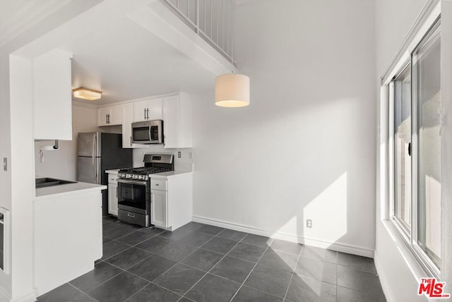 kitchen featuring dark tile patterned flooring, sink, white cabinetry, and stainless steel appliances