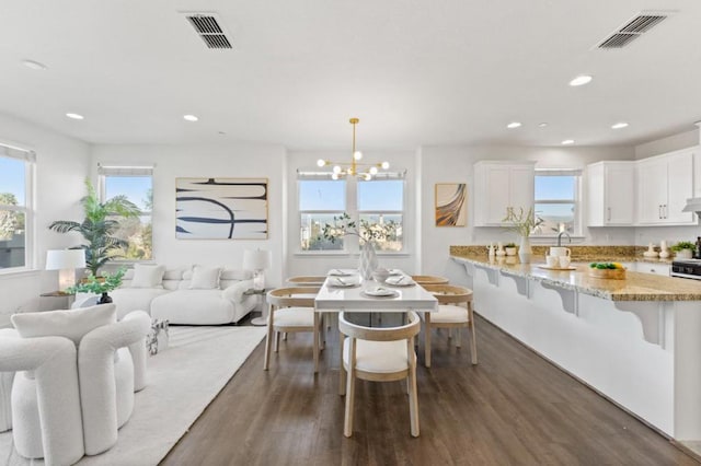 dining area with a notable chandelier, plenty of natural light, and dark hardwood / wood-style floors