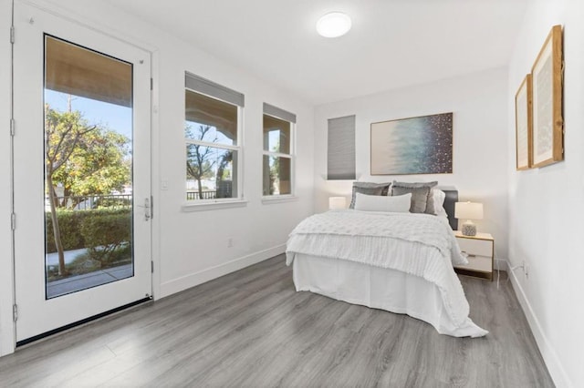 bedroom with hardwood / wood-style floors and access to outside