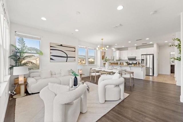 living room featuring plenty of natural light, a chandelier, and light hardwood / wood-style floors