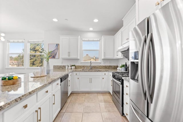 kitchen featuring sink, light tile patterned floors, stainless steel appliances, light stone countertops, and white cabinets