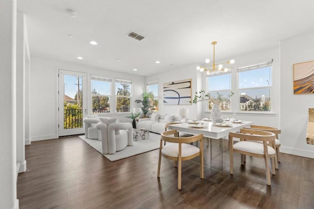 dining area featuring an inviting chandelier, a wealth of natural light, and dark hardwood / wood-style flooring