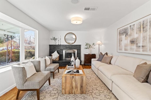 living room featuring a brick fireplace and light hardwood / wood-style floors