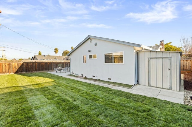 rear view of property featuring a yard, a patio area, and a storage unit