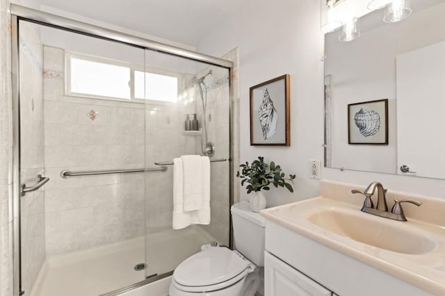 bathroom featuring vanity, toilet, and a shower with shower door