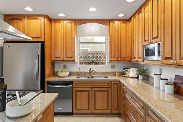 kitchen with sink, light stone counters, light tile patterned floors, appliances with stainless steel finishes, and wall chimney range hood