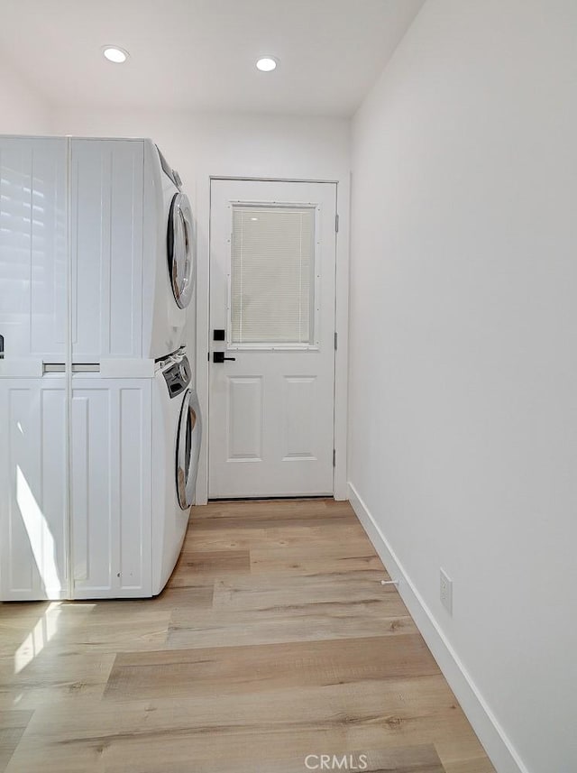 laundry area featuring light wood-type flooring and stacked washer and clothes dryer