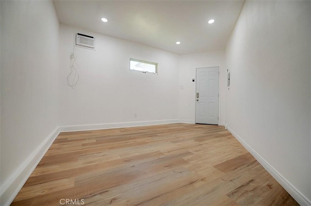 empty room with an AC wall unit and light hardwood / wood-style flooring