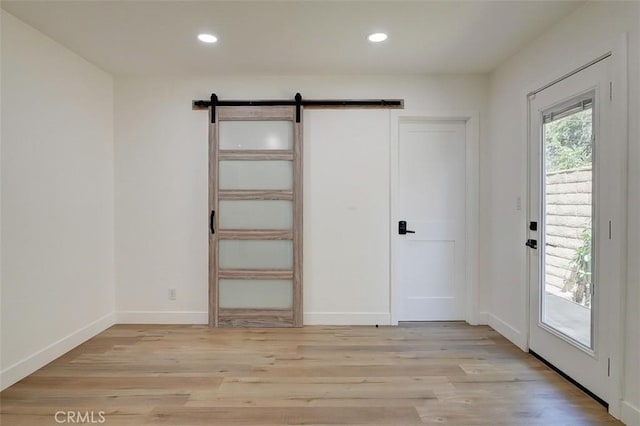 interior space featuring a barn door, light hardwood / wood-style flooring, and access to outside