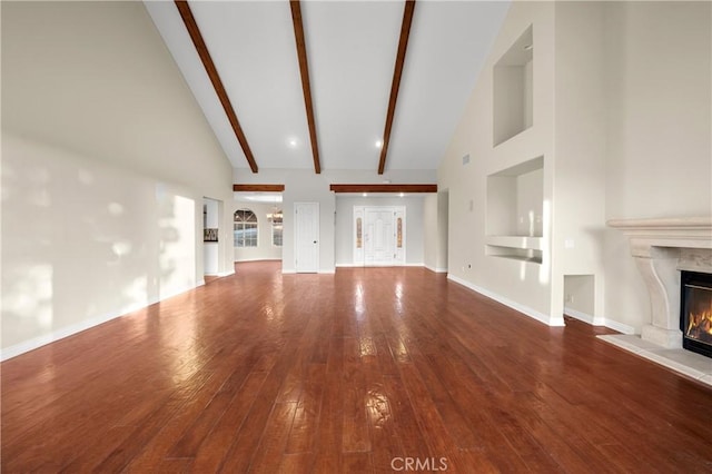 unfurnished living room with beamed ceiling, a premium fireplace, wood-type flooring, and high vaulted ceiling