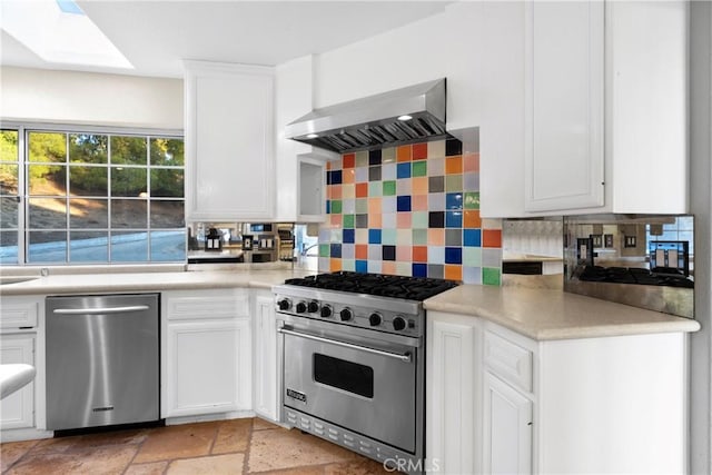 kitchen with white cabinets, stainless steel appliances, decorative backsplash, and wall chimney range hood