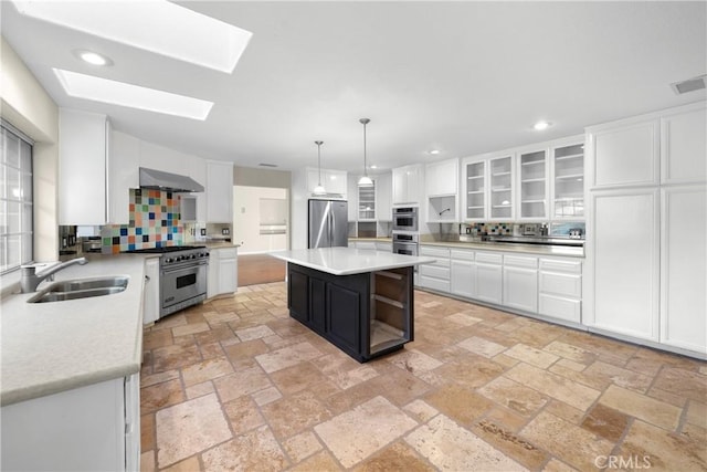 kitchen with pendant lighting, sink, a center island, stainless steel appliances, and wall chimney range hood