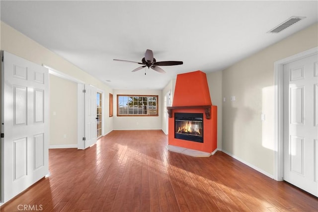 unfurnished living room featuring hardwood / wood-style flooring, a large fireplace, and ceiling fan