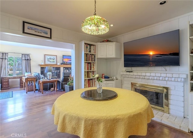 dining space with hardwood / wood-style flooring, built in features, crown molding, and a fireplace