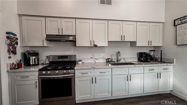 kitchen featuring sink, stainless steel range with gas cooktop, white cabinetry, dark hardwood / wood-style flooring, and light stone counters