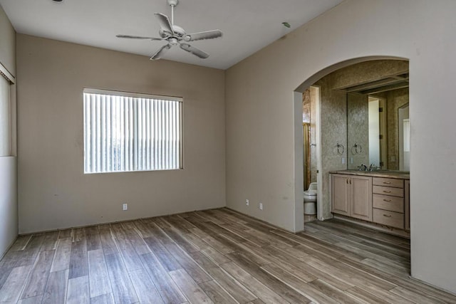 unfurnished bedroom with sink, light hardwood / wood-style floors, ensuite bath, and ceiling fan