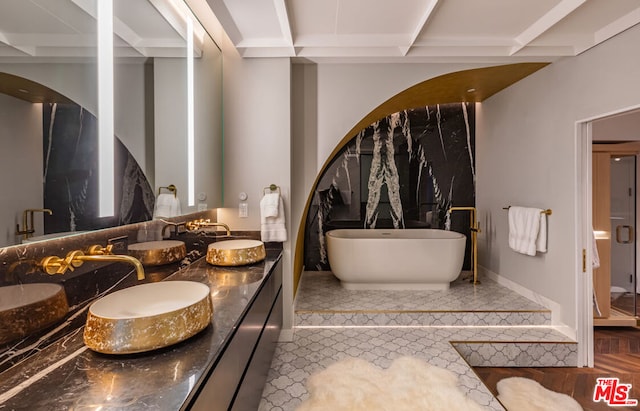 bathroom with a tub to relax in, vanity, and beamed ceiling