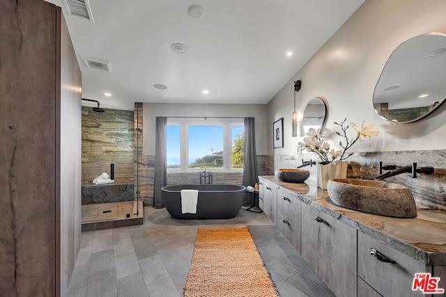 bathroom featuring tile patterned flooring, tile walls, separate shower and tub, and vanity