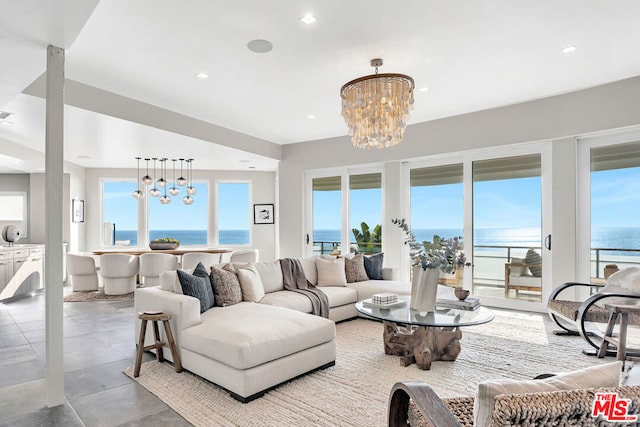 living room featuring plenty of natural light, a water view, and an inviting chandelier