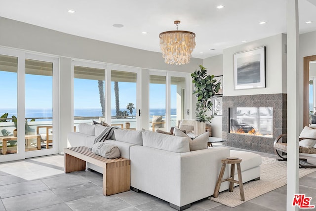 living room featuring a fireplace, a chandelier, a water view, and plenty of natural light