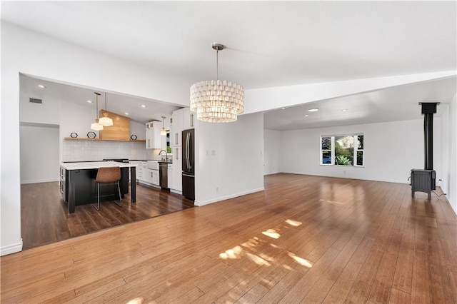 living room with sink, a wood stove, dark hardwood / wood-style floors, an inviting chandelier, and lofted ceiling