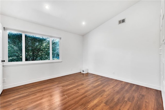 empty room with hardwood / wood-style flooring and vaulted ceiling