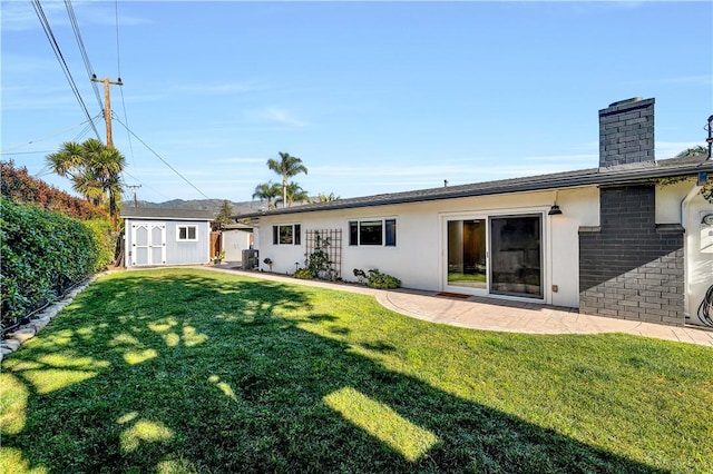 back of property with a patio, a lawn, and a shed