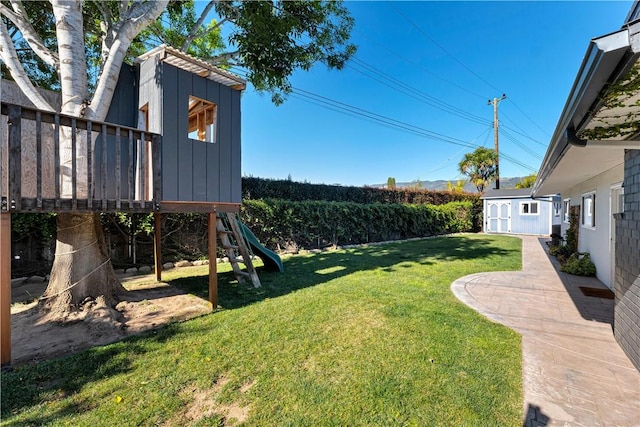 view of yard featuring a patio area, a playground, and a storage unit