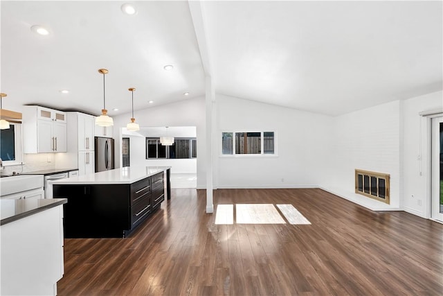 kitchen with stainless steel fridge, decorative light fixtures, white cabinets, a center island, and vaulted ceiling with beams