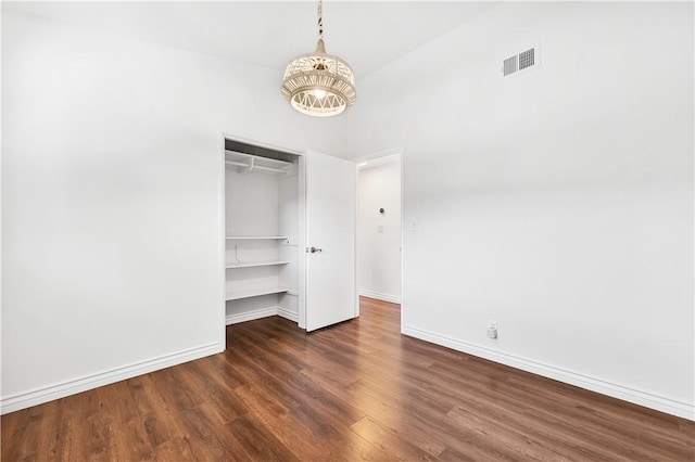 unfurnished bedroom with a closet, a high ceiling, and dark wood-type flooring