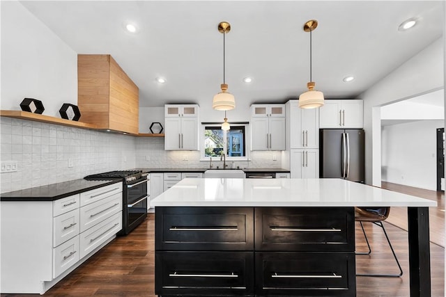 kitchen featuring stainless steel fridge, sink, white cabinets, range with two ovens, and a kitchen island