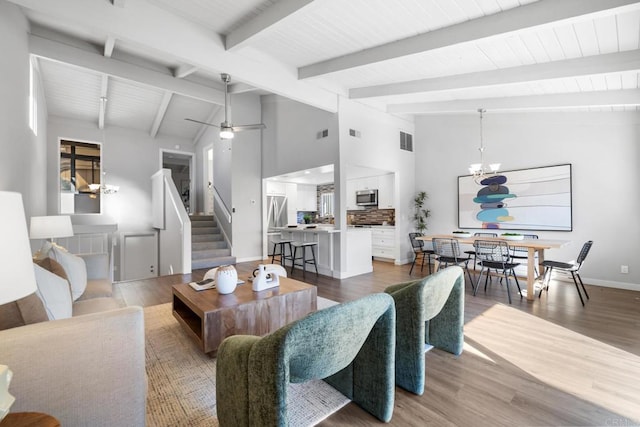 living room with high vaulted ceiling, ceiling fan with notable chandelier, wood-type flooring, and beamed ceiling