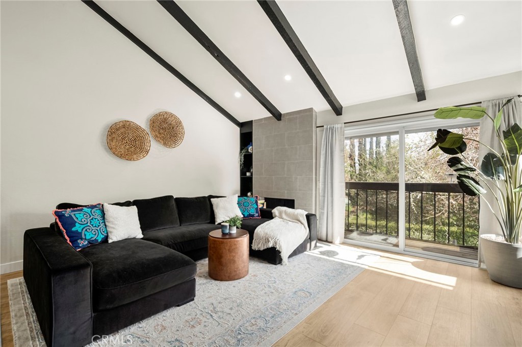 living room featuring wood-type flooring and vaulted ceiling with beams