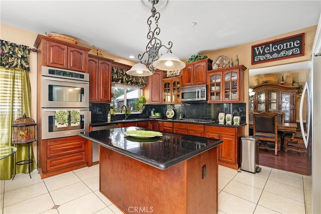 kitchen featuring appliances with stainless steel finishes, a center island, hanging light fixtures, and light tile patterned floors