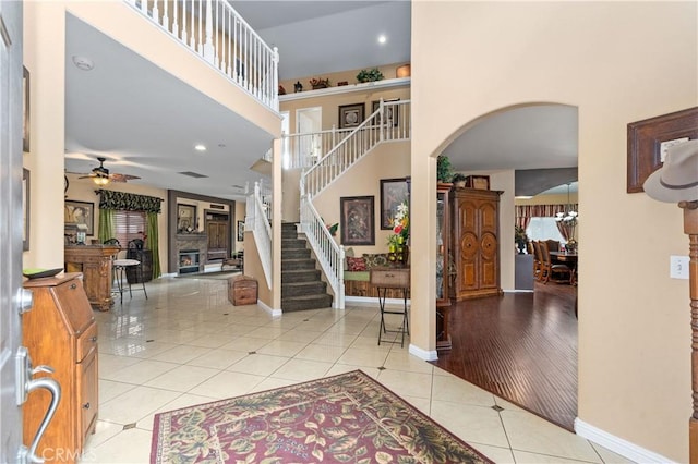 entryway featuring light tile patterned flooring, a towering ceiling, and ceiling fan