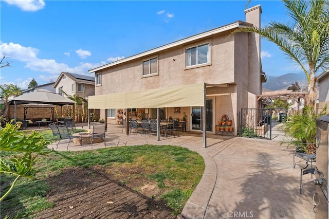 back of property with a gazebo, an outdoor fire pit, and a mountain view