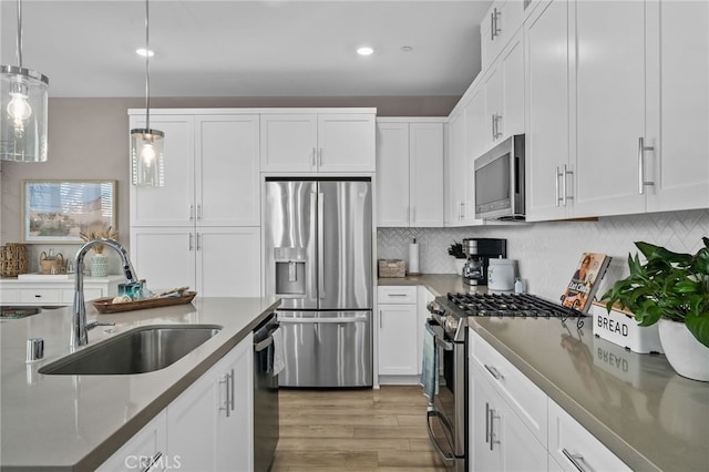 kitchen featuring sink, pendant lighting, white cabinets, and stainless steel appliances