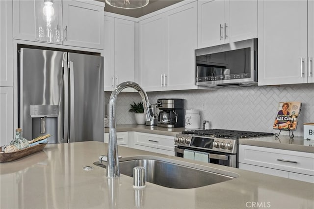 kitchen featuring white cabinets, backsplash, appliances with stainless steel finishes, and sink