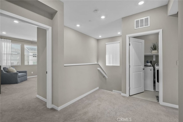 hall featuring light carpet and independent washer and dryer