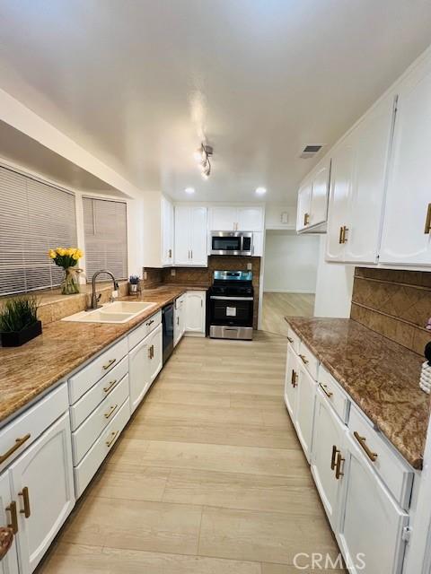 kitchen featuring white cabinetry, sink, dark stone countertops, and appliances with stainless steel finishes