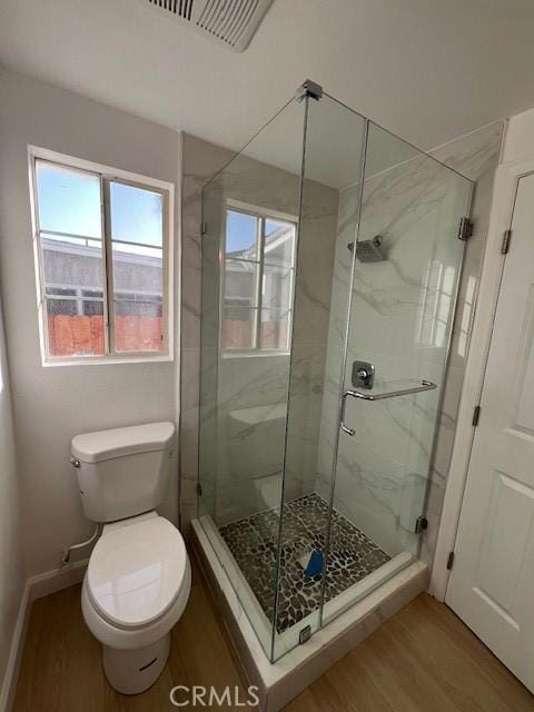 bathroom featuring wood-type flooring, toilet, and a shower with shower door