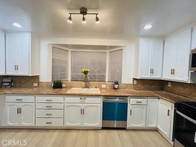 kitchen featuring stone counters, appliances with stainless steel finishes, tasteful backsplash, white cabinetry, and sink