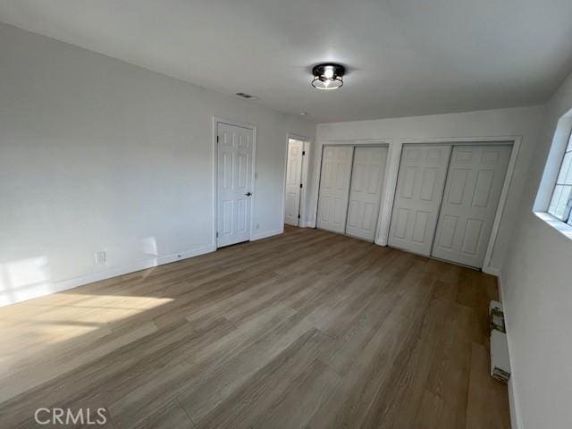 unfurnished bedroom featuring two closets and light hardwood / wood-style floors