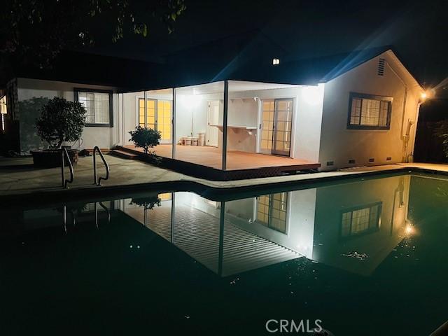 pool at night featuring a patio