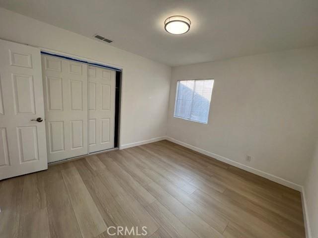 unfurnished bedroom with light hardwood / wood-style flooring and a closet