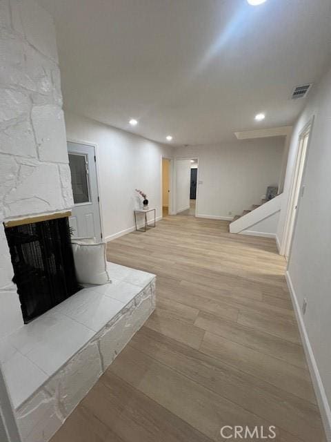 basement with a stone fireplace and light hardwood / wood-style floors