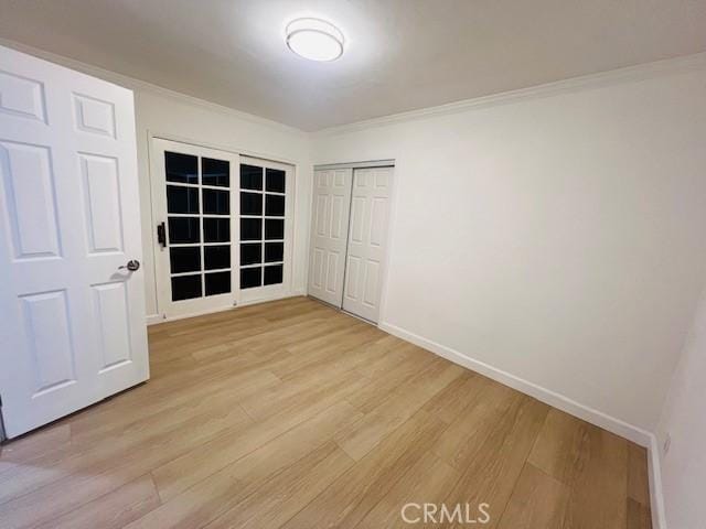 unfurnished bedroom with ornamental molding, light wood-type flooring, and a closet