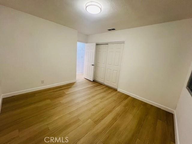 unfurnished bedroom featuring light hardwood / wood-style flooring and a closet